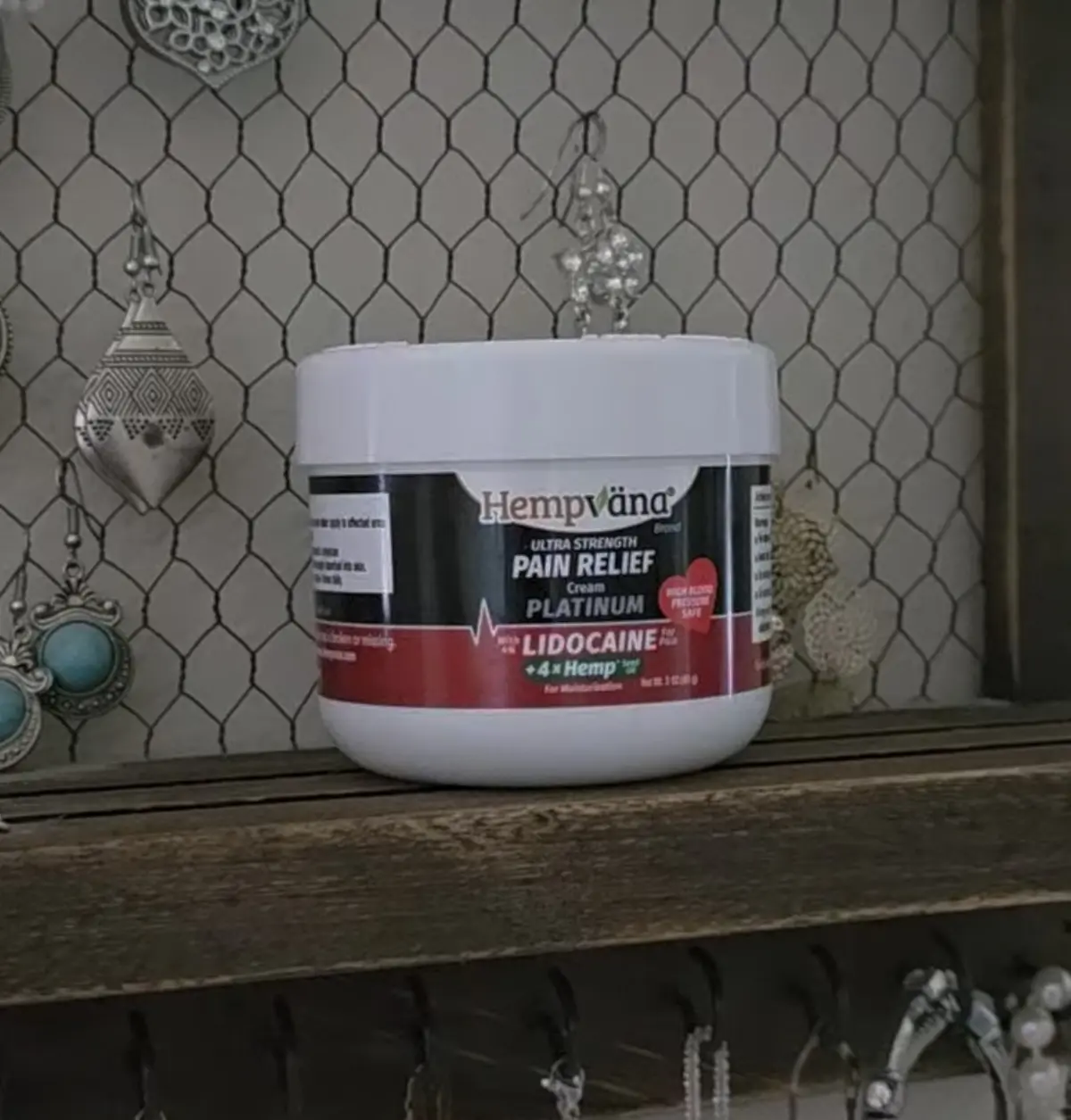 Hempvana Platinum Pain Relief Cream with lidocaine and hemp, styled on a rustic wooden shelf with chicken wire backdrop.