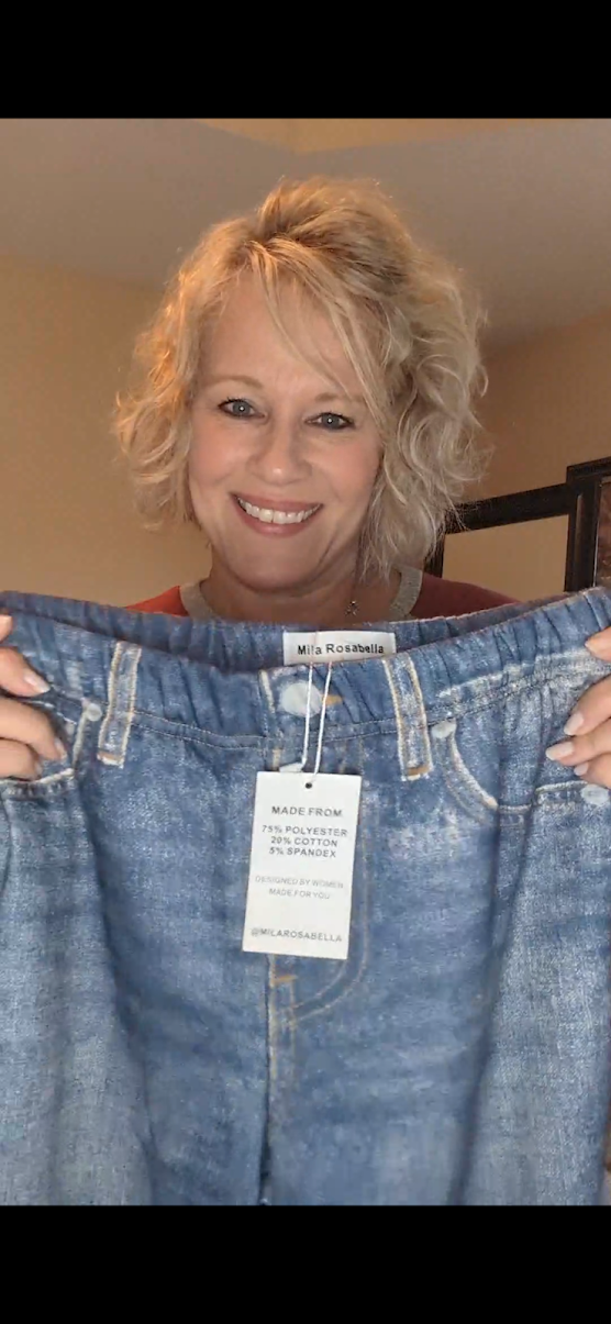 Alica Rutherford holding up a pair of comfortable everyday light-wash jeans with the tag still attached.